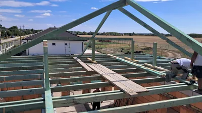 Érd – Álló tetőváz és vízszintes gerendák a ház falai felett, munka közben.