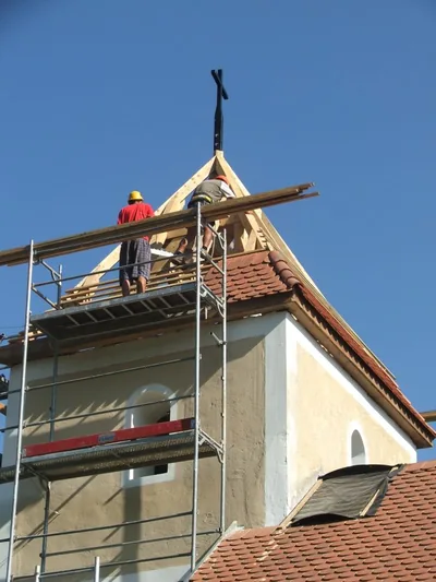 Budaörs – Szakemberek a kápolnatorony új cserépfedésén dolgoznak, a toronycsúcs alatt.