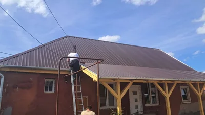Adony – Barna lemezfedés a ház tetején és a faoszlopos előtetőn, szerelés közben.