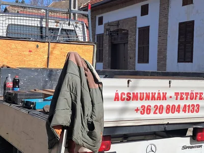 Budapest XXII. kerület – Ácsmunkák és tetőfedés feliratú platós autó a felújítás helyszínén.