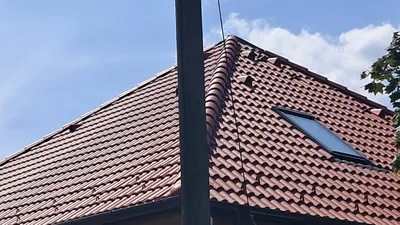 Százhalombatta – A kész vörös cserépfedés és tetőablak oldalnézetből, az előtérben oszloppal.